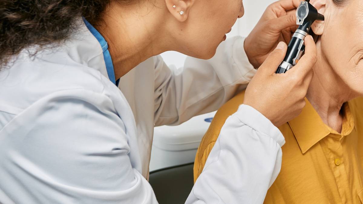 Lekarz bada ucho pacjenta otoskopem.