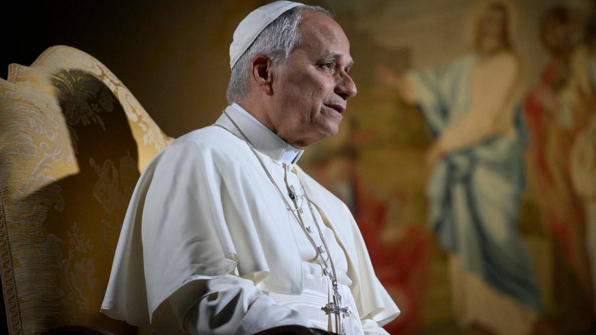 Papież Franciszek siedzi w fotelu, ubrany w białą sutannę i piuskę. W tle widoczny obraz religijny.