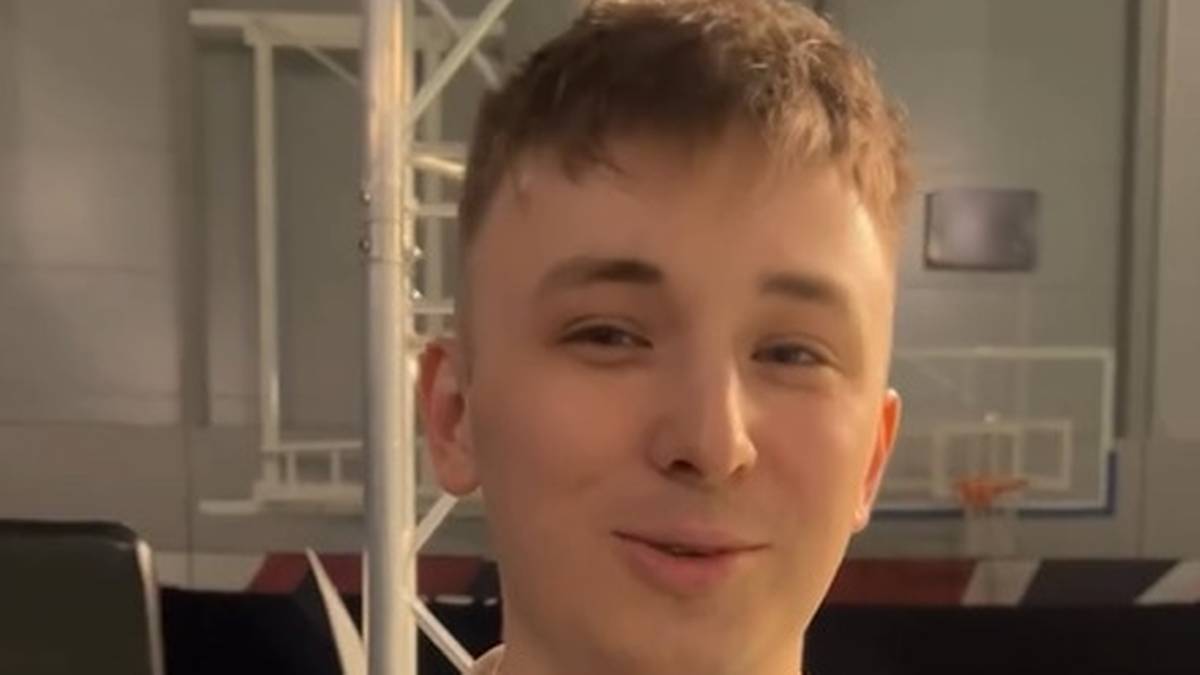 Portret młodego mężczyzny z kr&oacute;tkimi, jasnymi włosami i lekko uśmiechniętą twarzą.