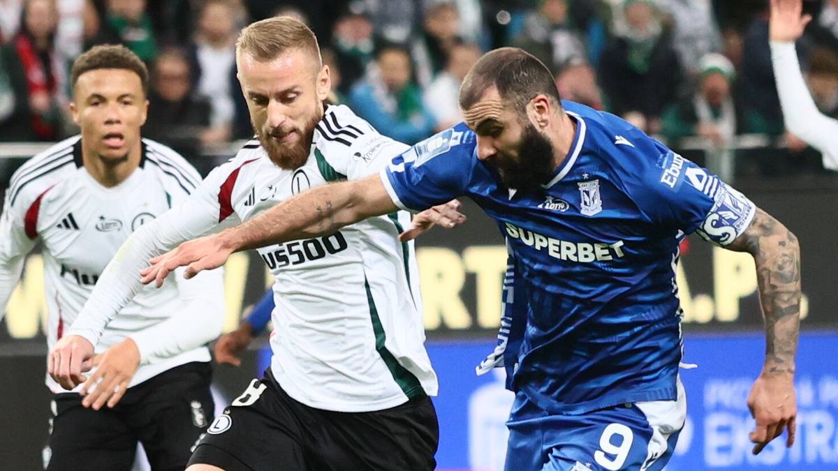 Dwóch piłkarzy walczy o piłkę podczas meczu piłki nożnej. Piłkarz w białej koszulce Legii Warszawa i piłkarz w niebieskiej koszulce przeciwnika są w zbliżeniu.