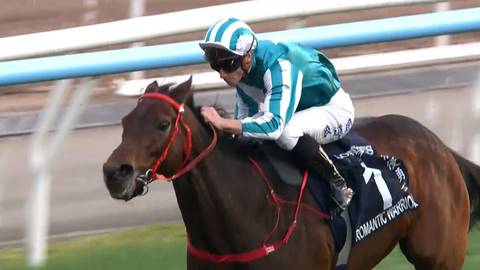 Jeździec w zielono-białym stroju, na koniu o imieniu Romantic Warrior, podczas wyścigu.