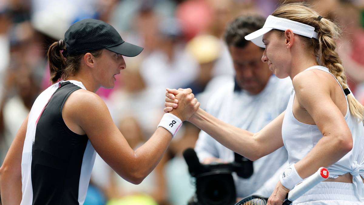 Dwie tenisistki uścisku dłoni przy siatce po meczu, obie w strojach sportowych.