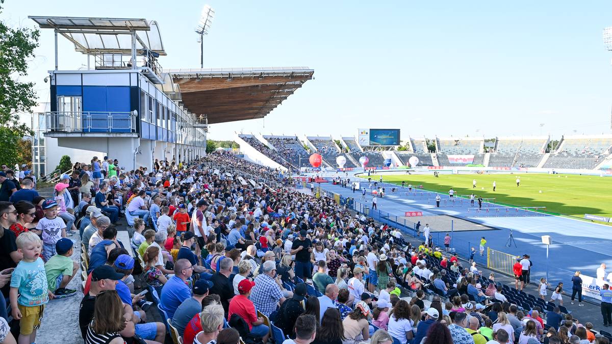 Widzowie siedzący na trybunach stadionu lekkoatletycznego podczas zawod&oacute;w sportowych.