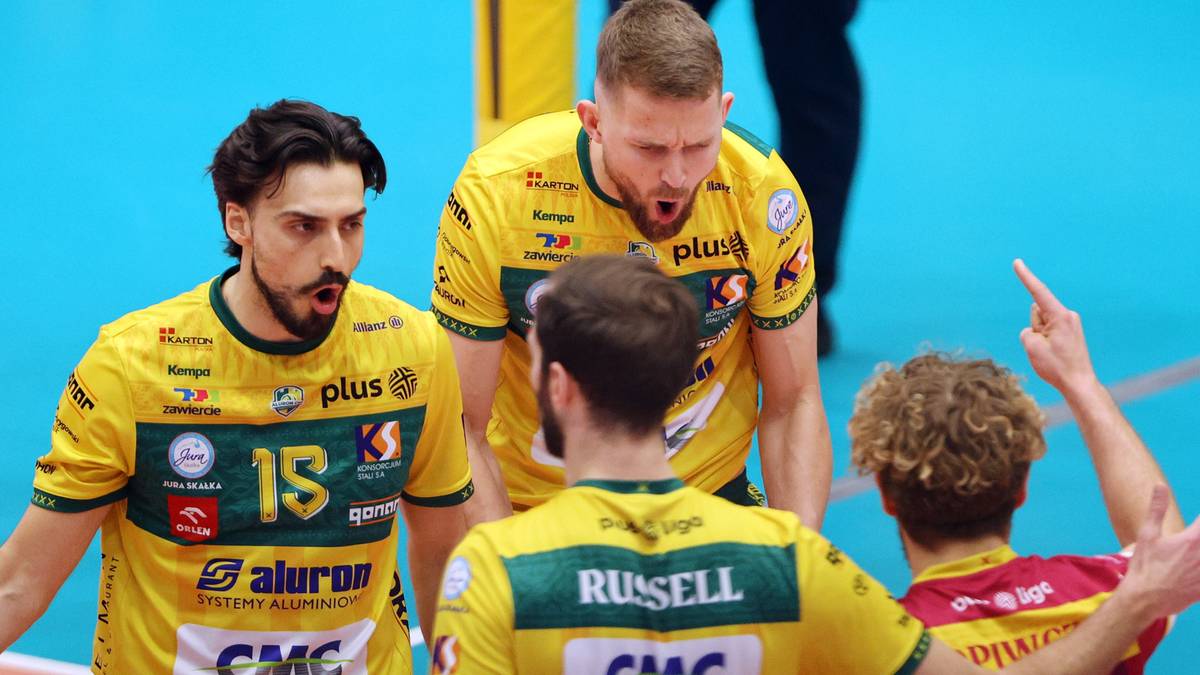 Czterech zawodnik&oacute;w drużyny siatkarskiej w ż&oacute;łtych koszulkach podczas meczu.