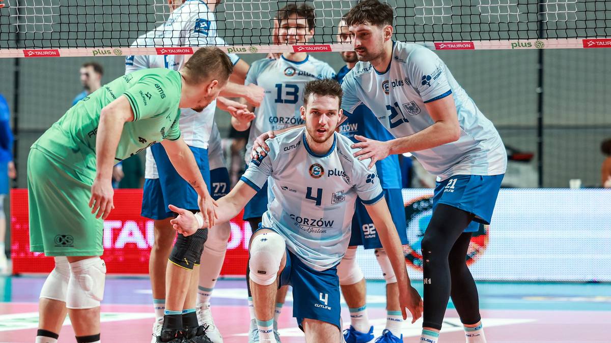 Siatkarze w jasnych strojach rywalizują na boisku, jeden z zawodnik&oacute;w klęczy z piłką.