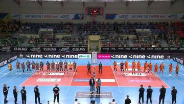 Drużyny siatkarskie Barkom Każany Lw&oacute;w i Trefl Gdańsk ustawione na boisku, gotowe do rozpoczęcia meczu, z widzami na trybunach.