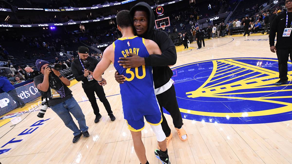 Dwóch koszykarzy Golden State Warriors przytulających się na boisku, jeden w niebieskim stroju z numerem 30.