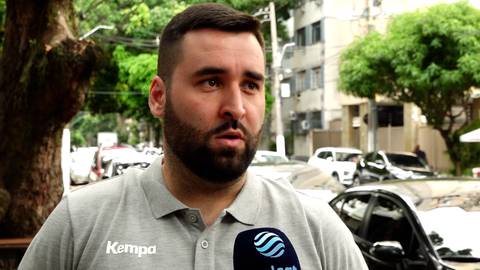 Portret mężczyzny w szarej koszulce z logo Kempa, trzymającego mikrofon.