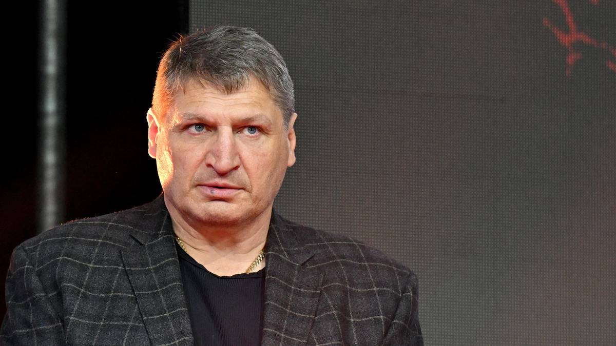 Portret Andrzeja Gołoty, polskiego boksera, z widocznym zamyśleniem na twarzy. Ubrany jest w szarą marynarkę w kratę.