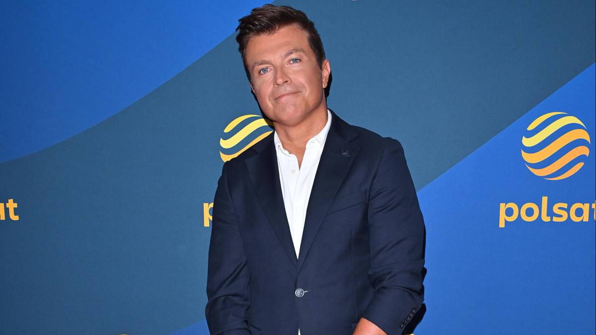 Bożydar Iwanow, prezenter telewizyjny, w granatowym garniturze i białej koszuli, uśmiecha się.