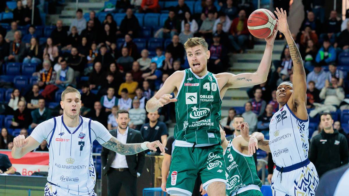 Zawodnicy walczący o piłkę pod koszem podczas meczu koszyk&oacute;wki.