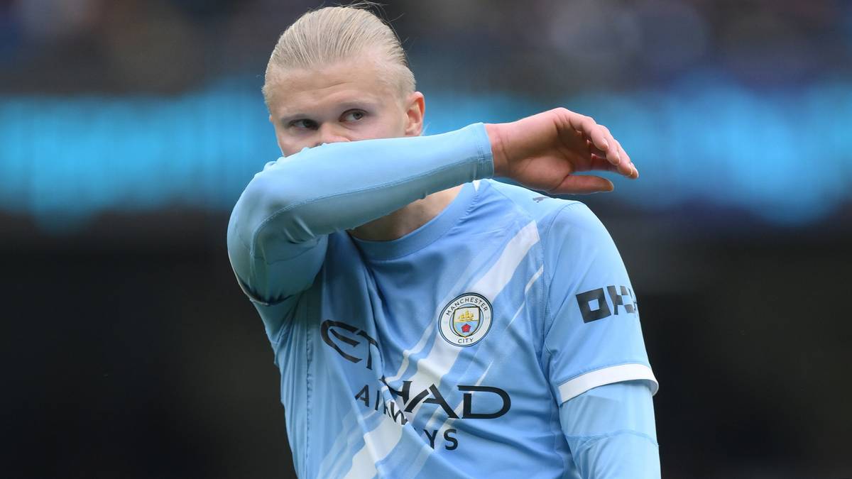 Erling Haaland w niebieskiej koszulce piłkarskiej Manchesteru City zakrywa twarz rękawem