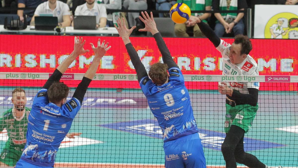 Siatkarze w akcji podczas meczu ligowego, jeden z nich wykonuje atak.