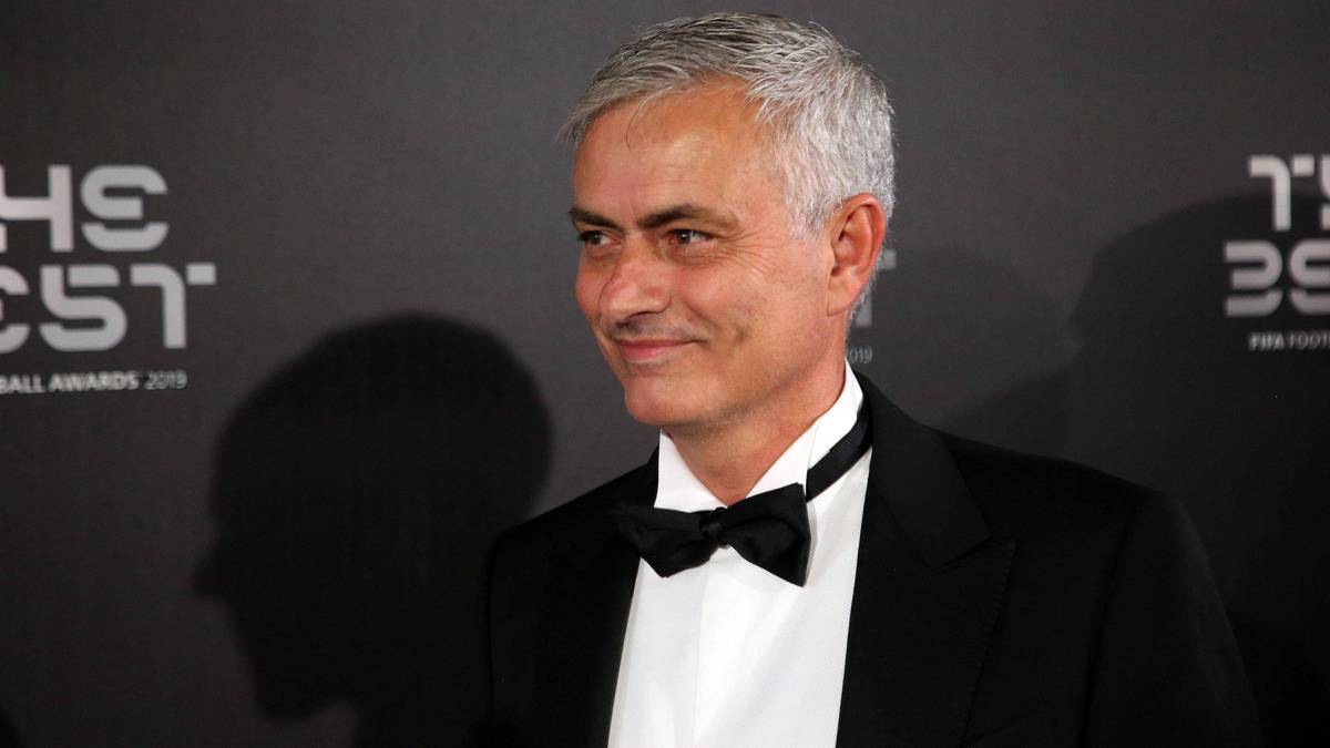 Portret Jose Mourinho w garniturze i muszce uśmiechającego się.