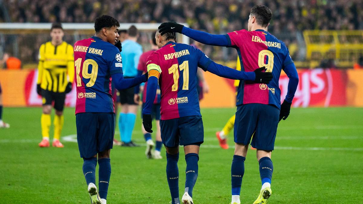 Trzech piłkarzy FC Barcelony świętuje gola na boisku. Dwóch z nich stoi tyłem do widza, jeden ma rękę na ramieniu drugiego.