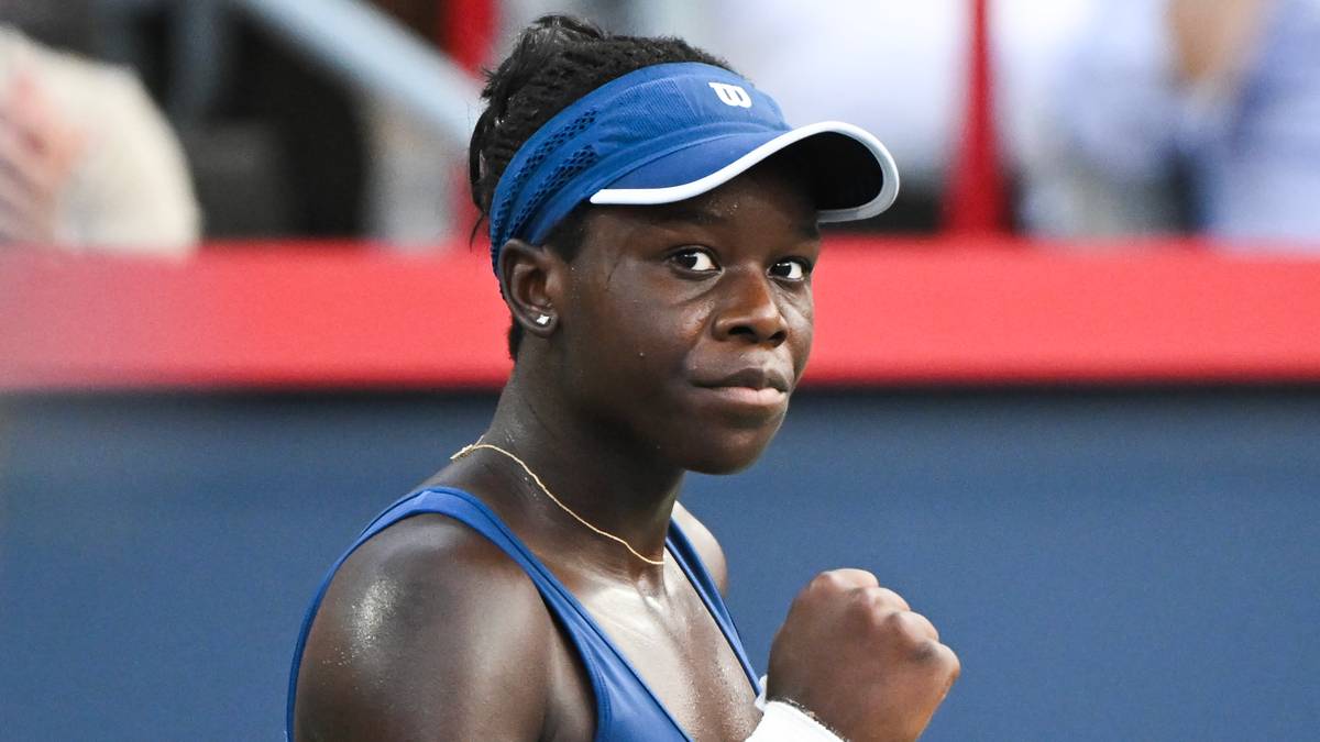 Portret młodej tenisistki w niebieskiej czapce i koszulce sportowej, patrzącej w bok z determinacją.