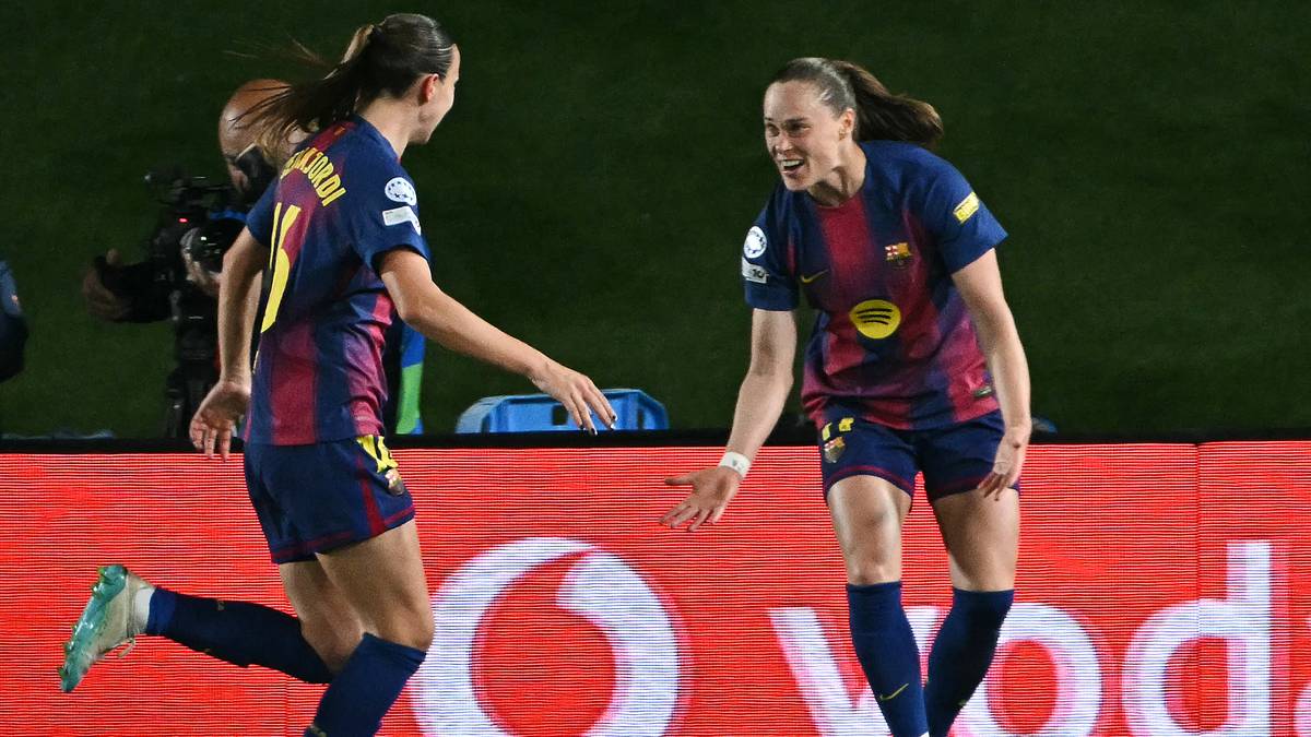 Dwie piłkarki w granatowo-bordowych strojach FC Barcelony cieszą się z sukcesu na boisku. Jedna z nich podaje rękę drugiej, kt&oacute;ra biegnie w jej kierunku.
