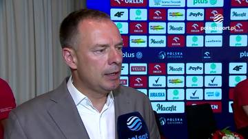 Piotr Borys udziela wywiadu przed ścianą z logo sponsor&oacute;w.