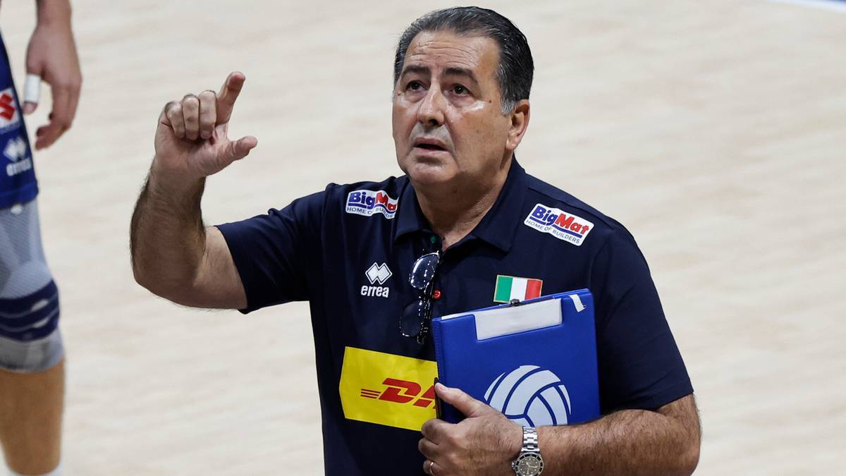 Siatkarski trener w średnim wieku, wskazujący palcem i trzymający notes z piłką siatkówką.