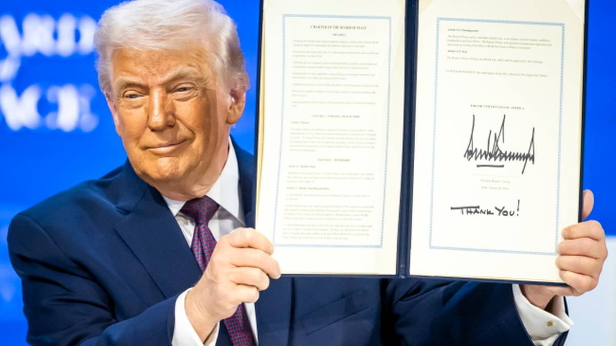 Donald Trump trzyma otwarty dokument z podpisami, prezentując go.