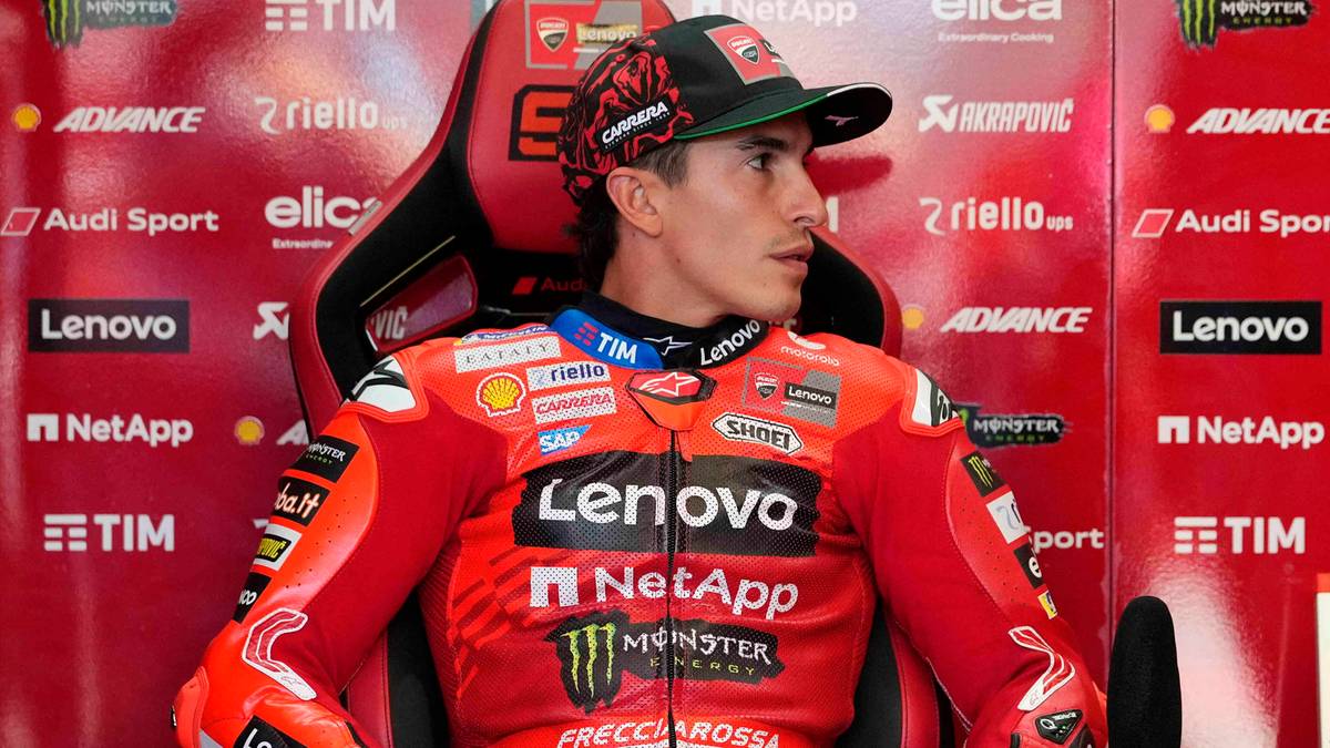 Alex Marquez, zawodnik MotoGP, siedzi w czerwonym fotelu wyścigowym, ubrany w kombinezon wyścigowy z logotypami sponsorów.