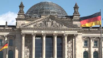 Budynek Reichstagu w Berlinie z kopułą i flagą Niemiec.