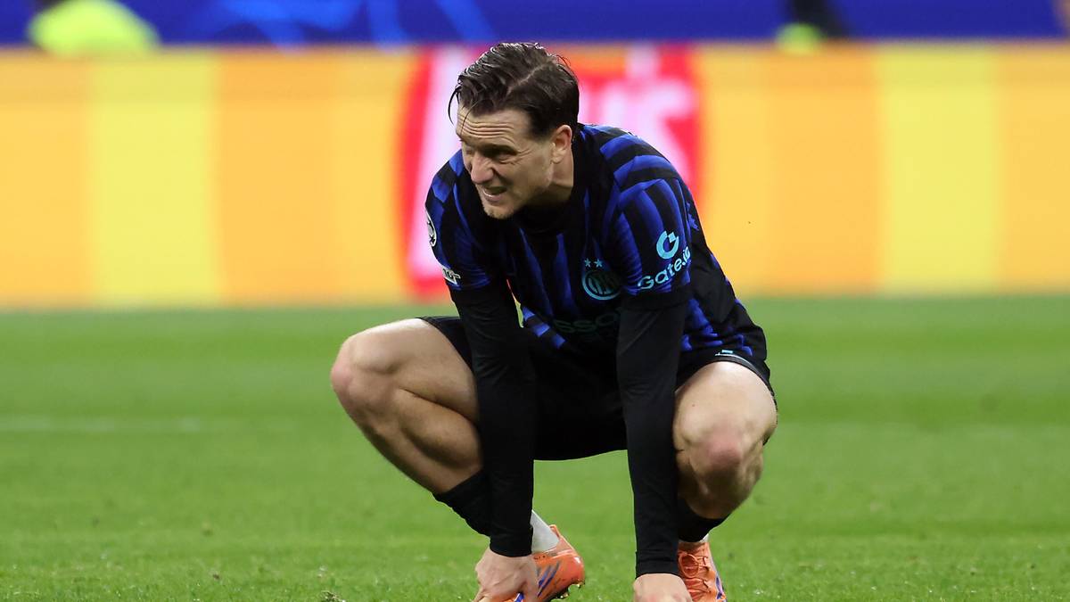 Piłkarz w niebiesko-czarnej koszulce Interu Mediolan kuca na zielonej murawie stadionu.