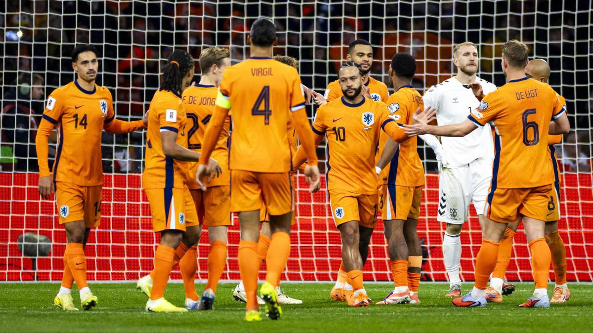 Drużyna piłkarska Holandii w pomarańczowych strojach stoi przed bramką.