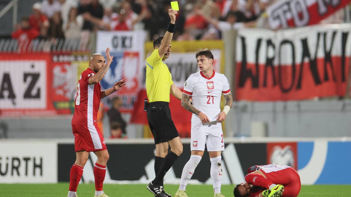 Sędzia pokazuje żółtą kartkę piłkarzowi reprezentacji Polski w białej koszulce.