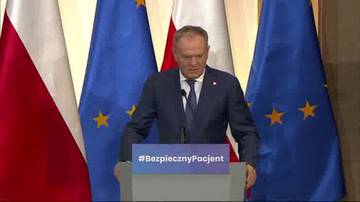 Donald Tusk stoi przy mównicy z napisem "#BezpiecznyPacjent", na tle flag Polski i Unii Europejskiej.