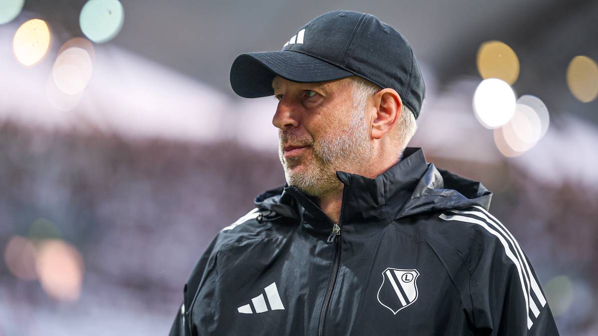 Mężczyzna w czapce z daszkiem i kurtce sportowej z emblematem klubu, patrzy w bok.