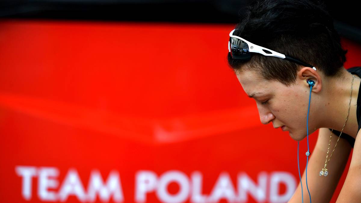 Sportowiec w słuchawkach, na tle czerwonego tła z napisem TEAM POLAND.