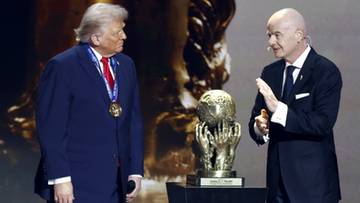 Donald Trump i Gianni Infantino stoją obok siebie, patrząc na złote trofeum w kształcie kuli ziemskiej, które trzymają ręce.