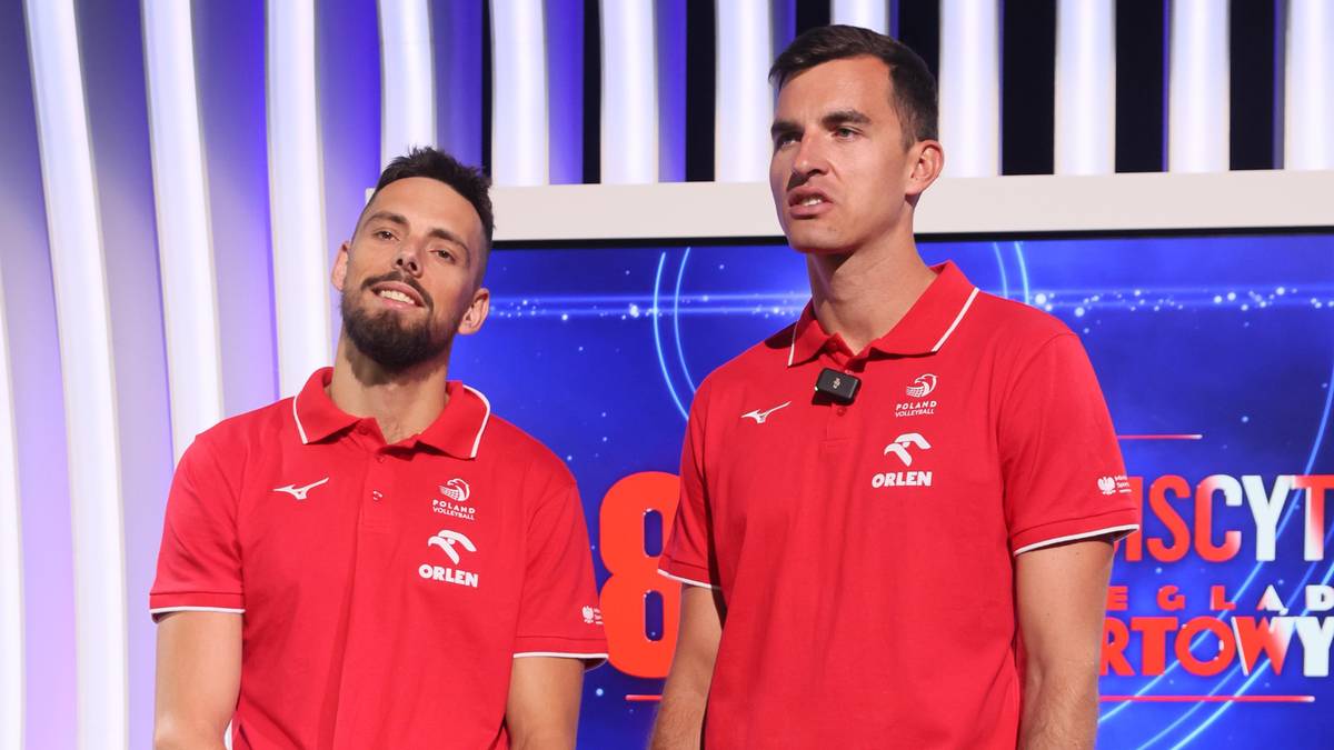 Dwóch polskich siatkarzy w czerwonych koszulkach z białymi wstawkami i logo, patrzących w różne strony.