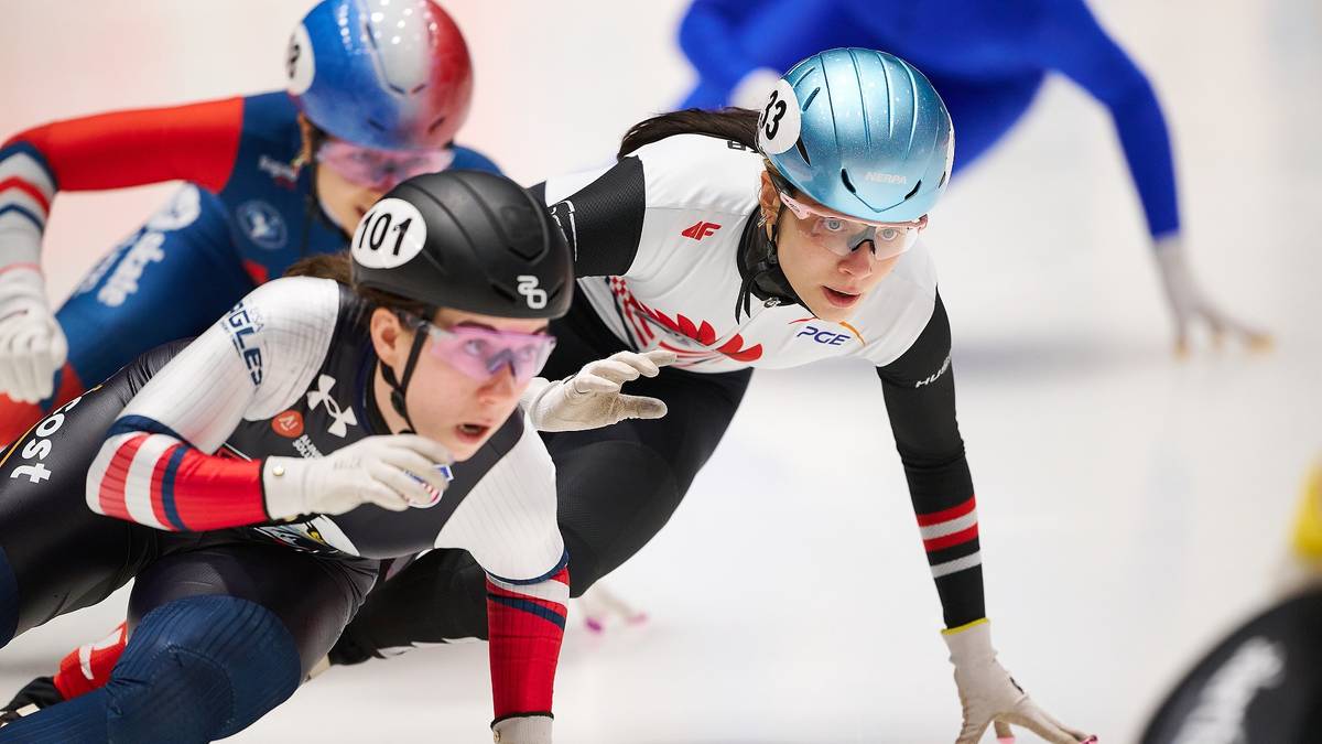 Trzy łyżwiarki short track na lodowisku podczas zawodów.