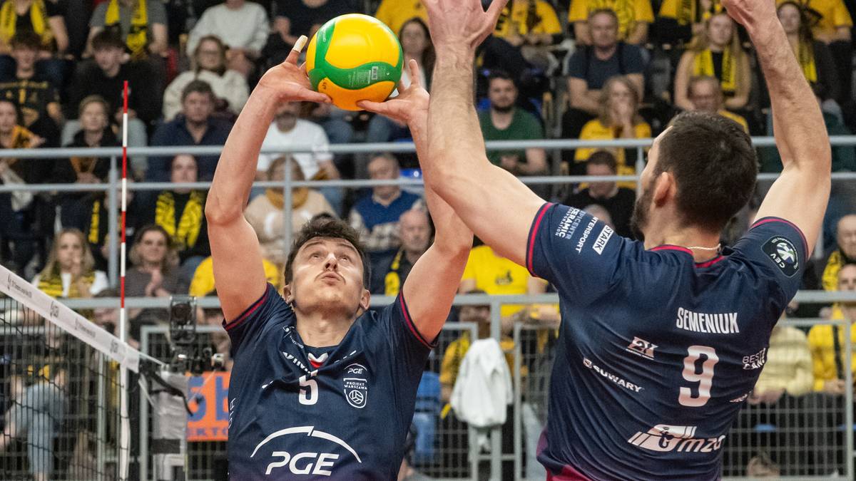 Siatkarz PGE Projekt Warszawa z numerem 5 podrzuca piłkę do serwisu, a obok niego siatkarz z numerem 9 w bloku.
