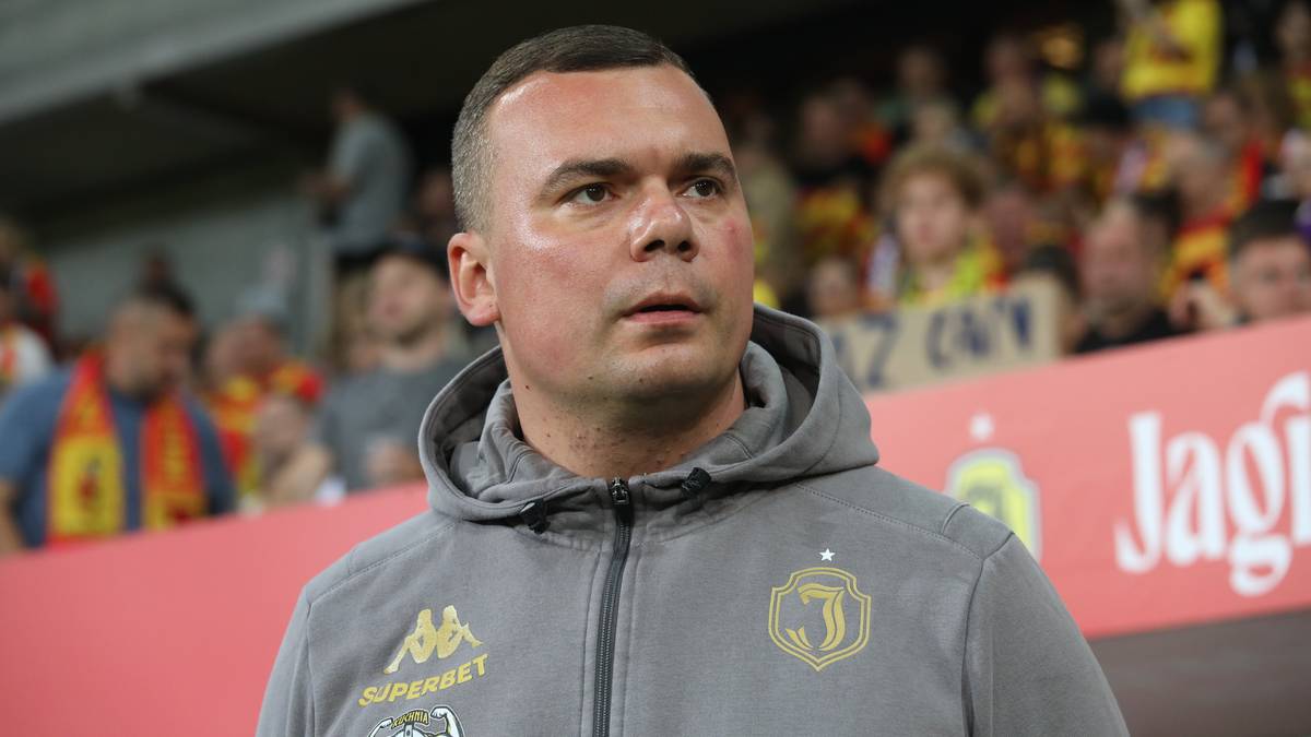 Adrian Siemieniec, trener Jagiellonii Białystok, ubrany w szarą bluzę z kapturem, patrzy przed siebie.