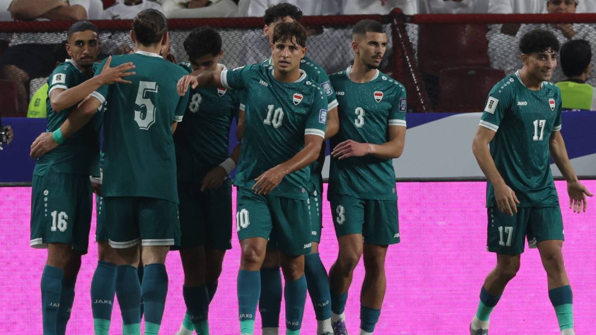 Drużyna piłkarska Iraku w zielonych strojach świętuje na boisku.
