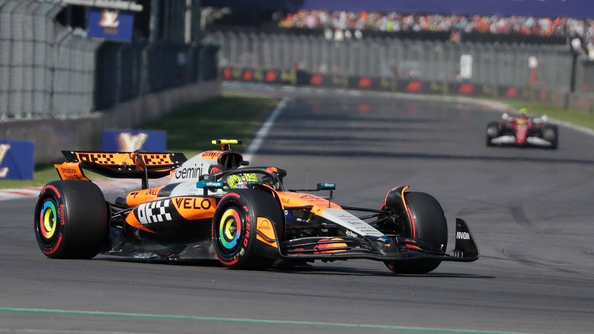 Samoch&oacute;d Formuły 1 zespołu McLaren z widocznym numerem 4, w jaskrawych barwach pomarańczowego, białego i czarnego, z tęczowymi akcentami na kołach, na torze wyścigowym.