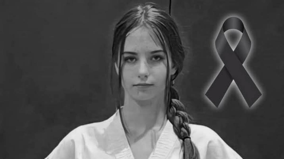 Młoda kobieta w stroju do taekwon-do, z czarną wstążką symbolizującą żałobę w prawym g&oacute;rnym rogu.