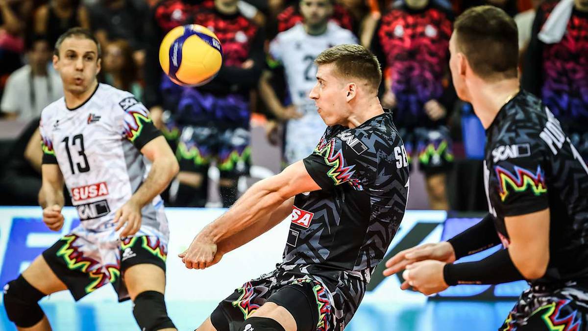 Siatkarz w czarno-szarym stroju z numerem 5 odbija piłkę sposobem dolnym, podczas meczu siatk&oacute;wki.