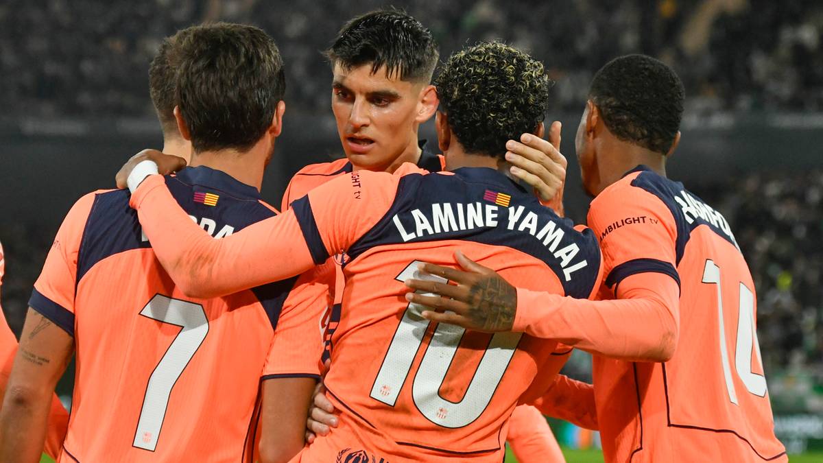 Czterech piłkarzy w pomarańczowych strojach świętuje razem, obejmując się.