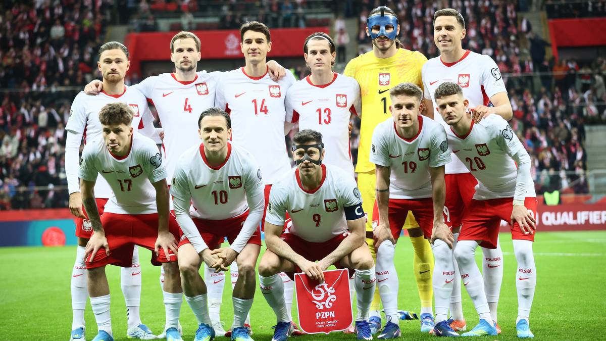 Piłkarze reprezentacji Polski w strojach meczowych pozują do zdjęcia na boisku.