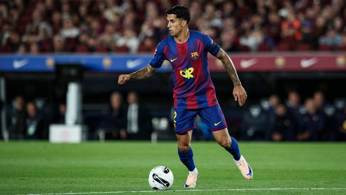 Piłkarz FC Barcelony w bordowo-granatowym stroju prowadzi piłkę na boisku.