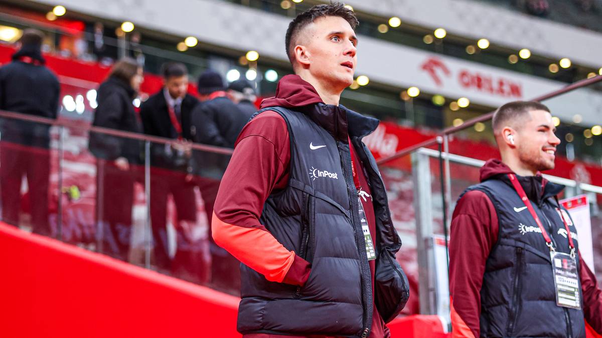 Dwóch polskich piłkarzy w strojach reprezentacji Polski na tle trybun.