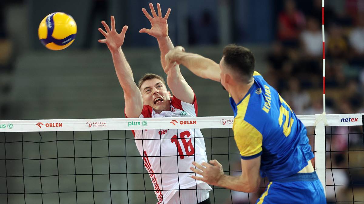 Dwóch siatkarzy podczas meczu, jeden z nich próbuje zablokować piłkę nad siatką.