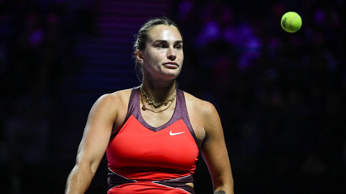 Aryna Sabalenka, tenisistka w czerwonym stroju sportowym, podczas meczu z piłką tenisową w powietrzu.