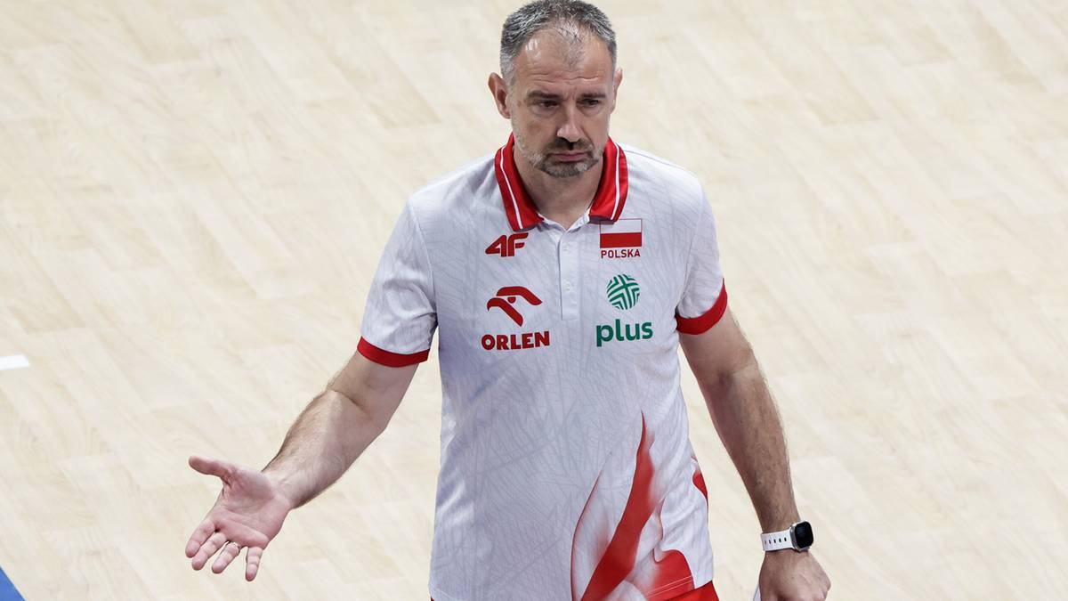 Trener reprezentacji Polski w siatkówce, Igor Grbić, w białej koszulce z logo 4F i Orlenu, gestykuluje rękami podczas meczu.