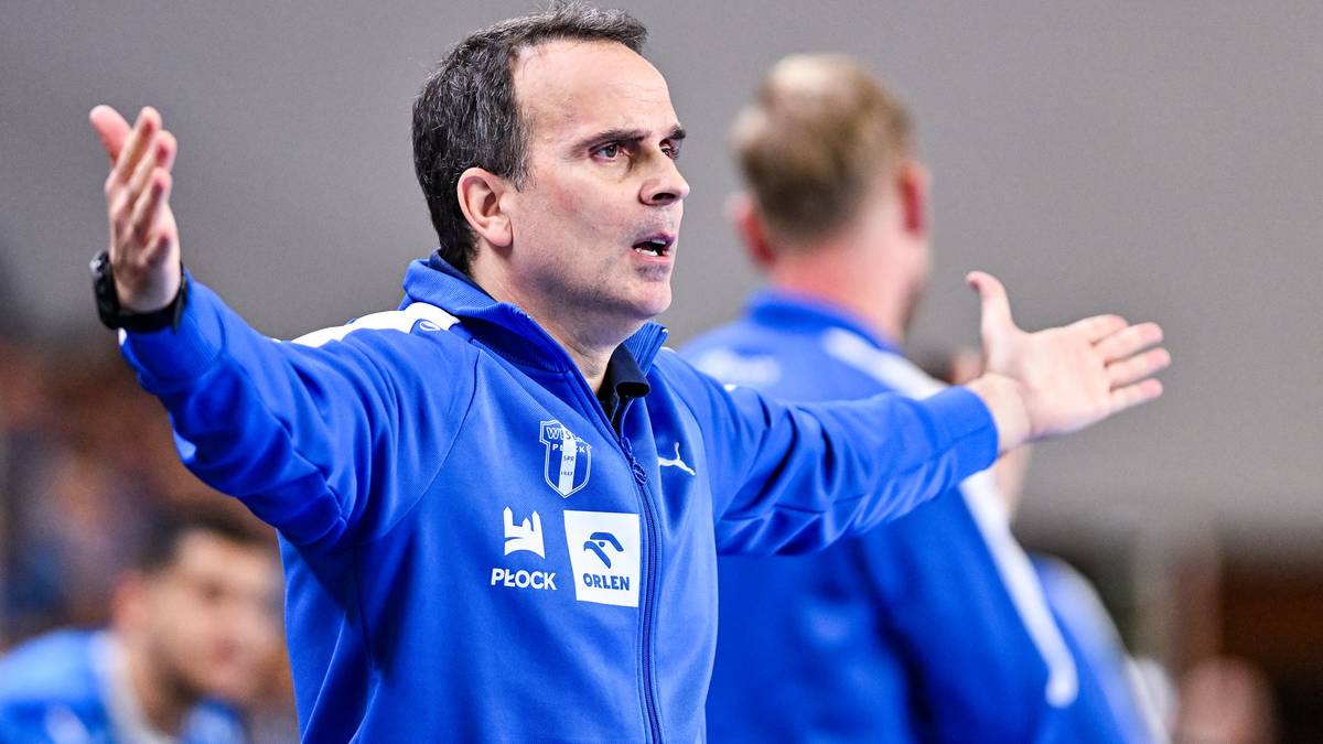 Mężczyzna w niebieskiej kurtce sportowej z otwartymi dłońmi, w geście frustracji lub ekscytacji.