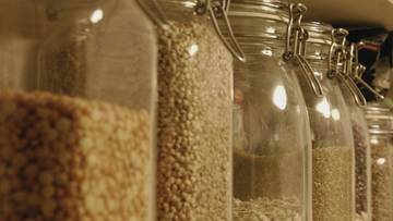 Rząd przezroczystych słoik&oacute;w wypełnionych r&oacute;żnymi rodzajami ziaren i nasion.